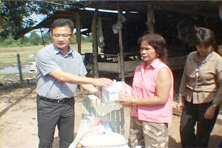 Deputy Mayor Wutisak Rermkitkarn, left, hands over some emergency living provisions to distraught homeowner Noi Pumart.